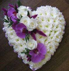 Heart-shaped white floral arrangement with purple orchids and white roses.