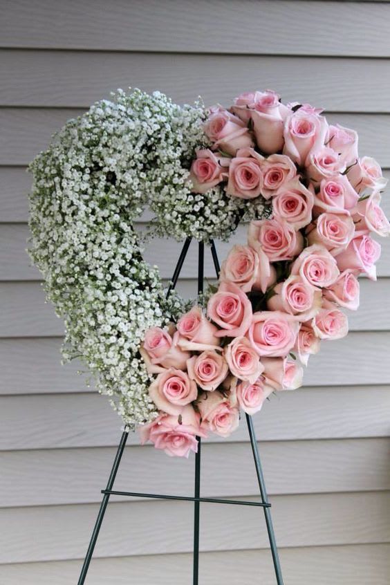 Heart-shaped standing wreath with pink roses and white filler flowers on a metal easel