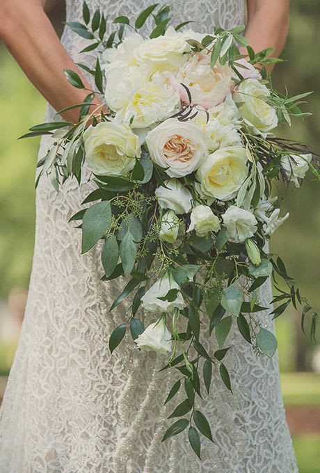 Cascading bridal bouquet of white and cream roses with trailing foliage
