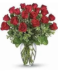Arrangement of red roses with foliage in a clear glass vase