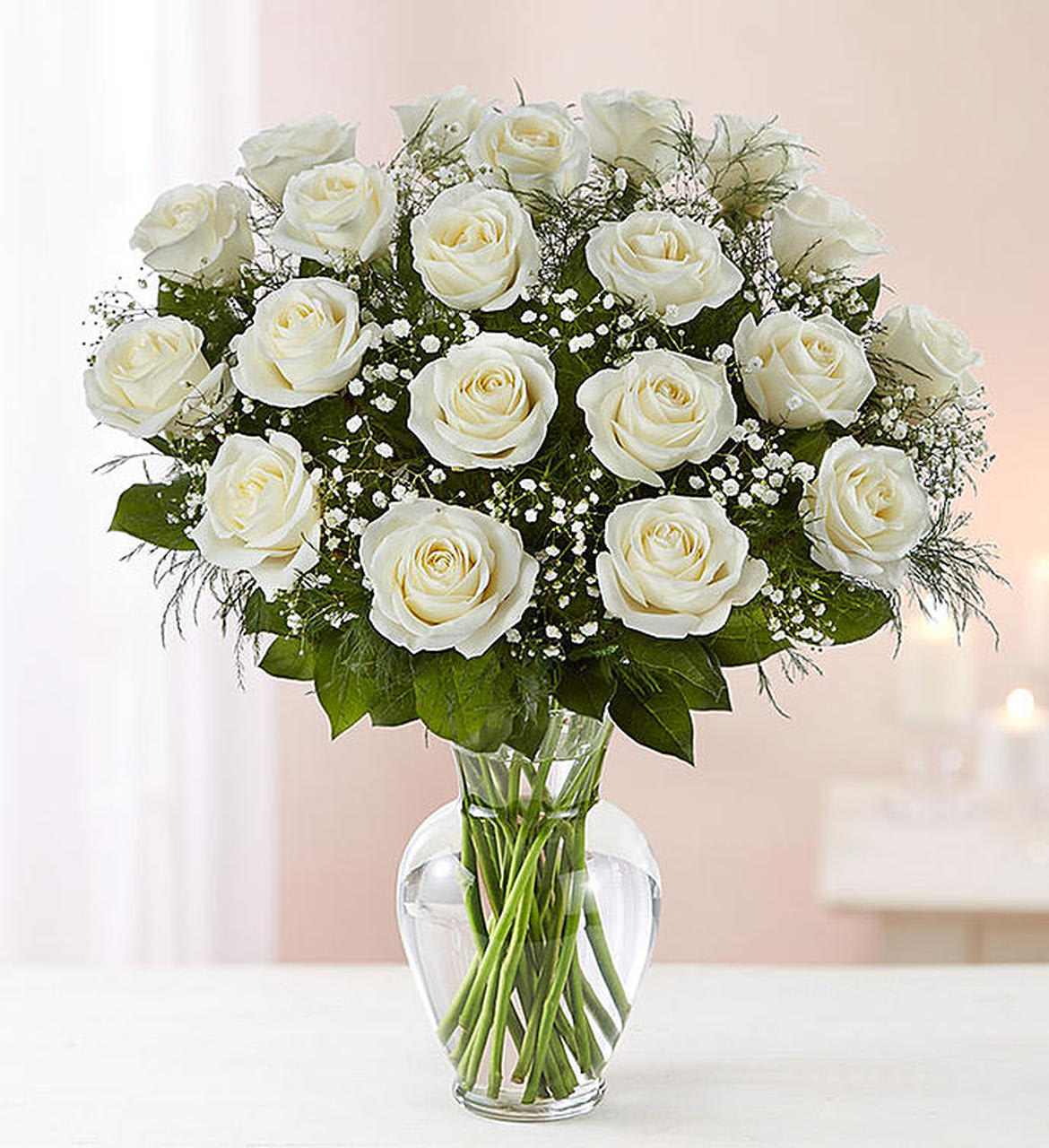 Arrangement of white roses with filler flowers in a clear glass vase