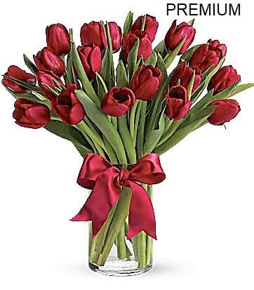 Arrangement of red tulips in a clear glass vase with a red ribbon bow