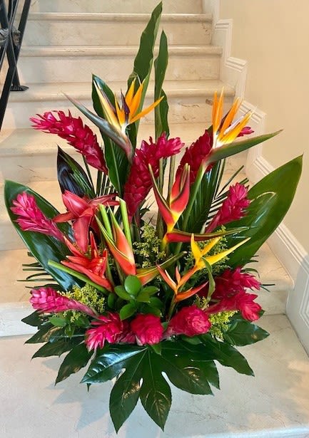 Tall tropical arrangement with red and orange flowers and large glossy leaves