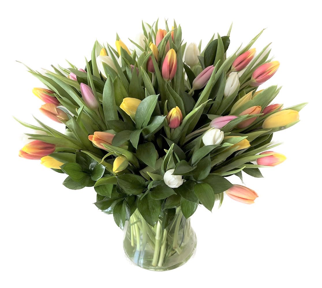 Large bouquet of mixed pastel tulips arranged in a clear glass vase