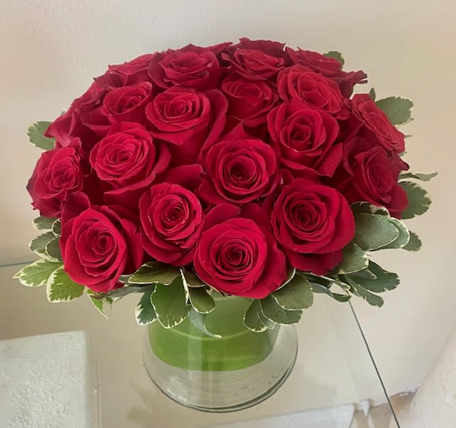Compact dome of red roses in a clear glass vase