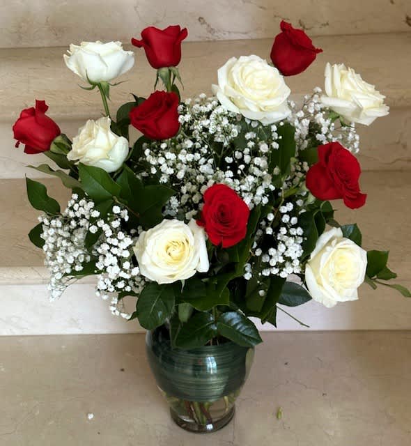 Red and white roses arranged in a glass vase with baby's breath