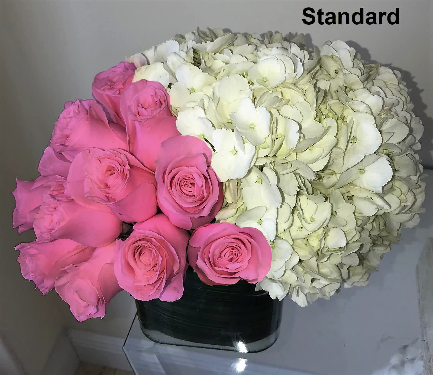 Low arrangement of pink roses and white hydrangeas in a square glass vase