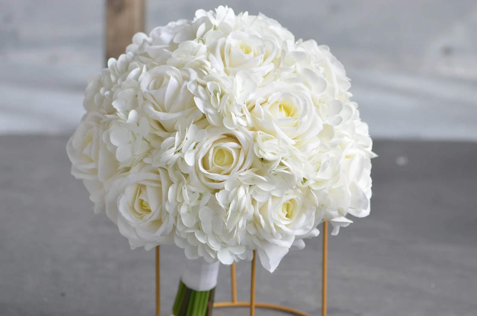 Round bridal bouquet of white roses and hydrangeas with wrapped stems