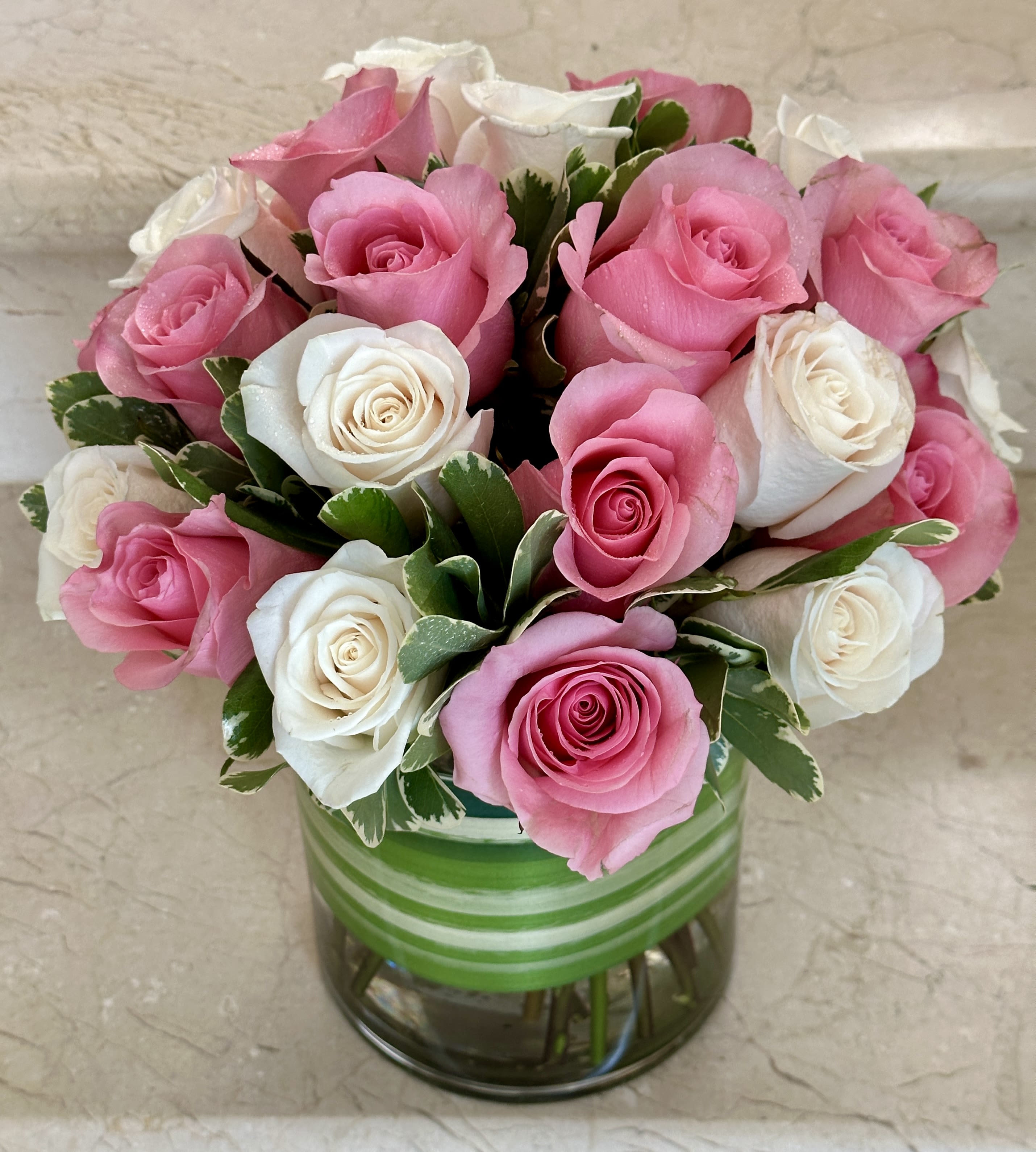 Pink and white roses arranged in a glass vase