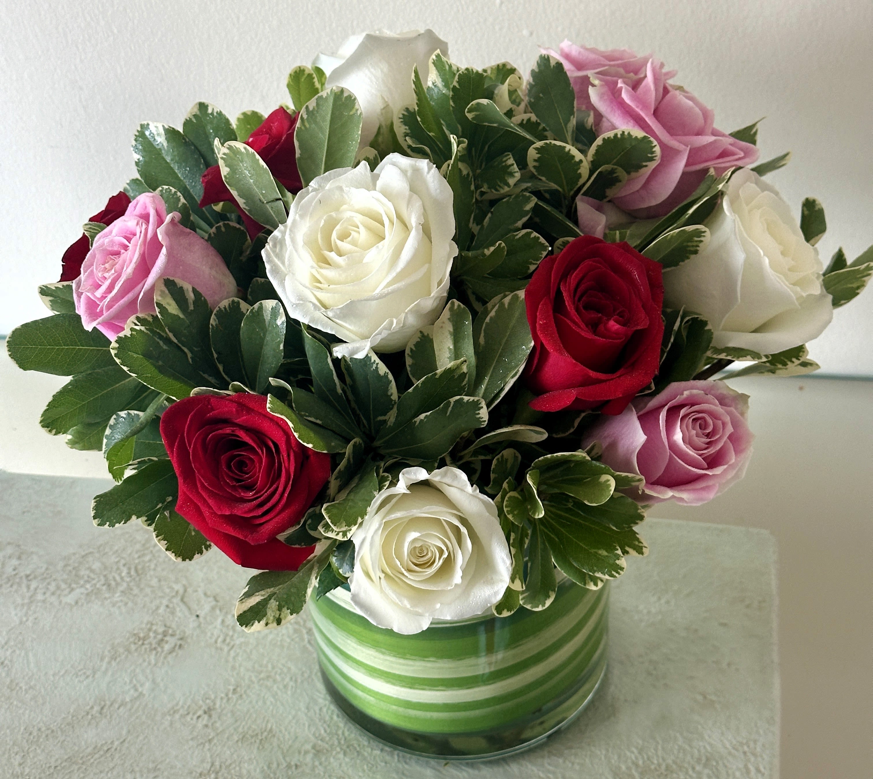 Bouquet of red, white, and pink roses in a striped glass vase