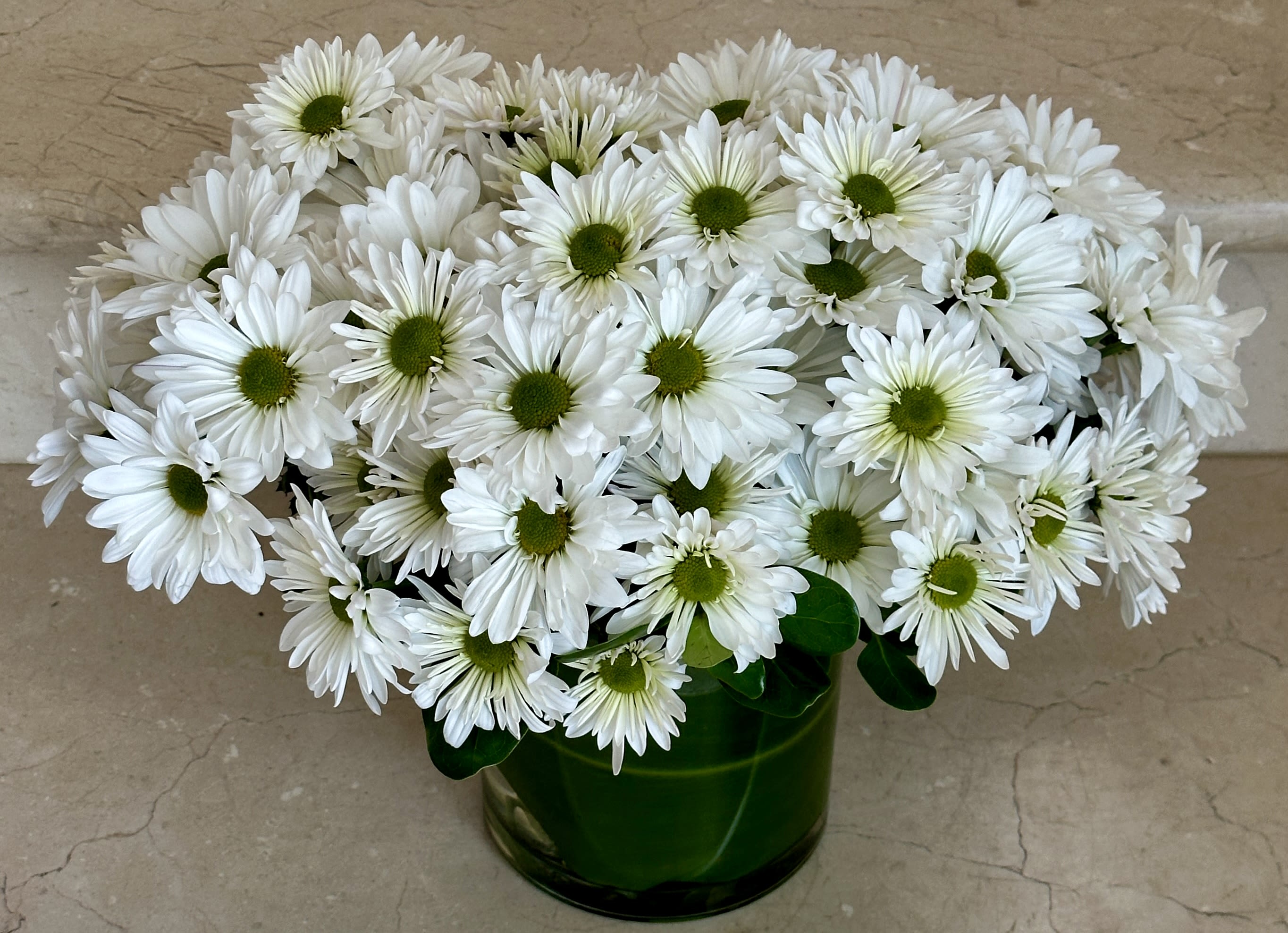White daisy bouquet in a green glass vase