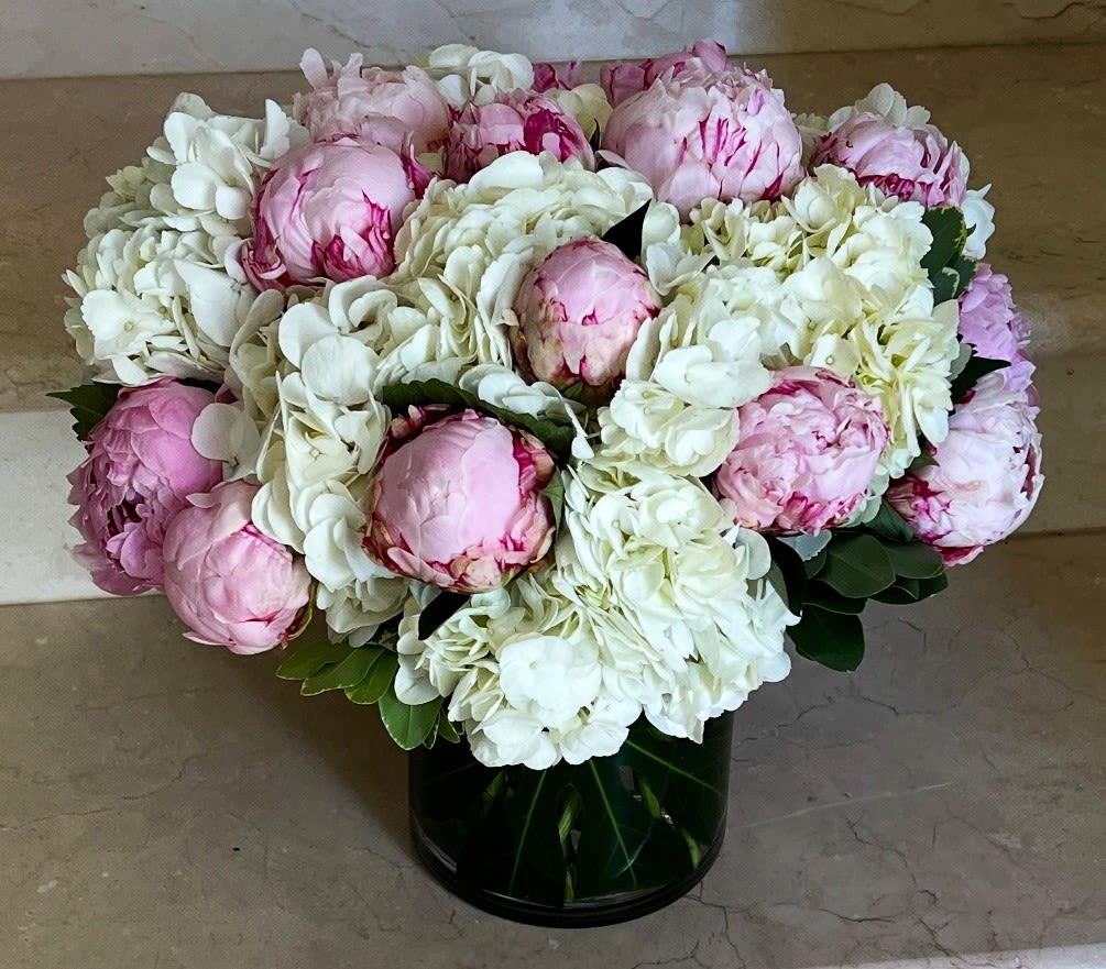Pink peonies and white hydrangeas in a dark glass vase