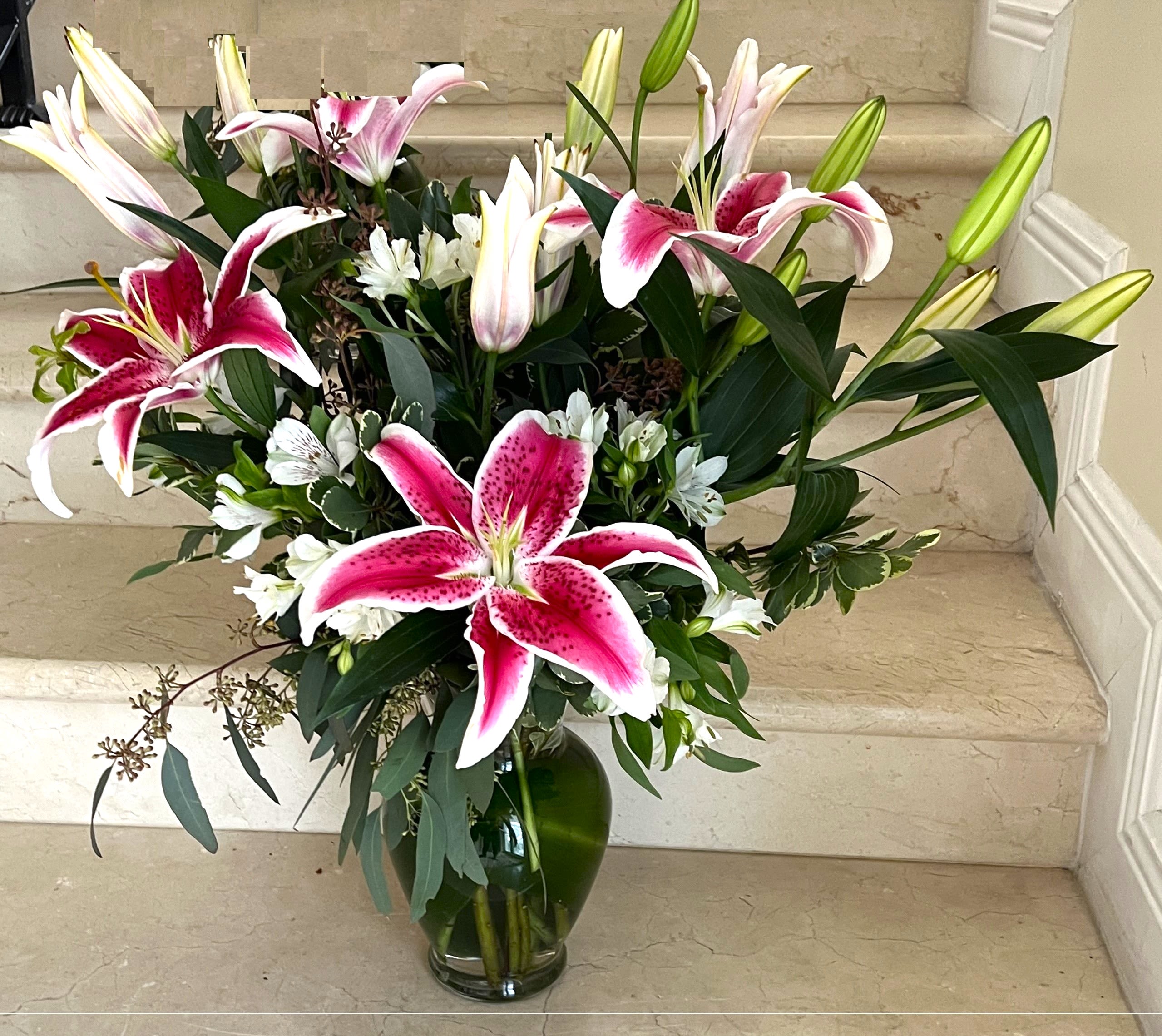 Pink and white lilies arranged in a glass vase