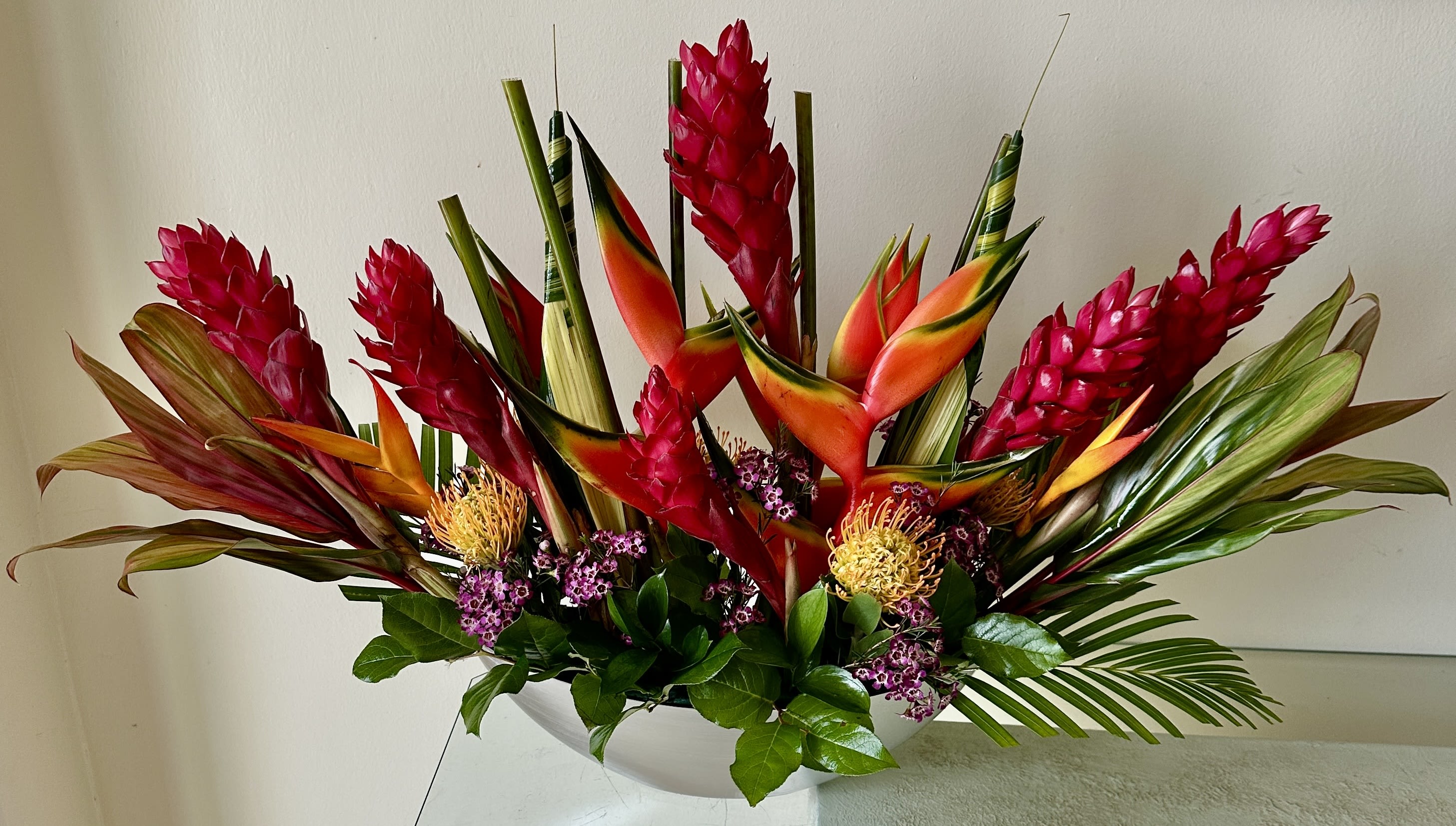 Tropical arrangement with red ginger and orange bird-of-paradise in a white bowl