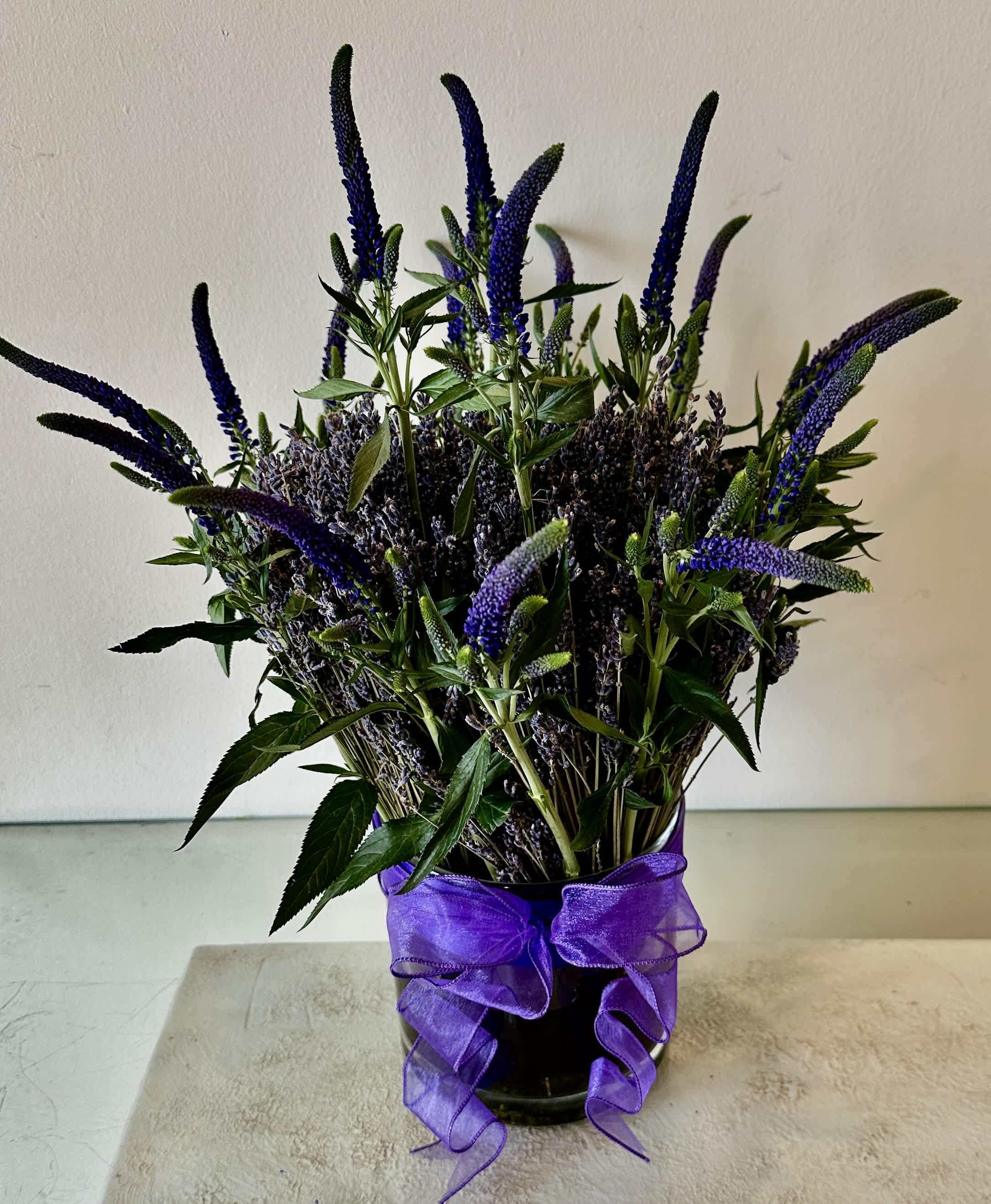 Purple flower arrangement in a glass vase with a ribbon bow