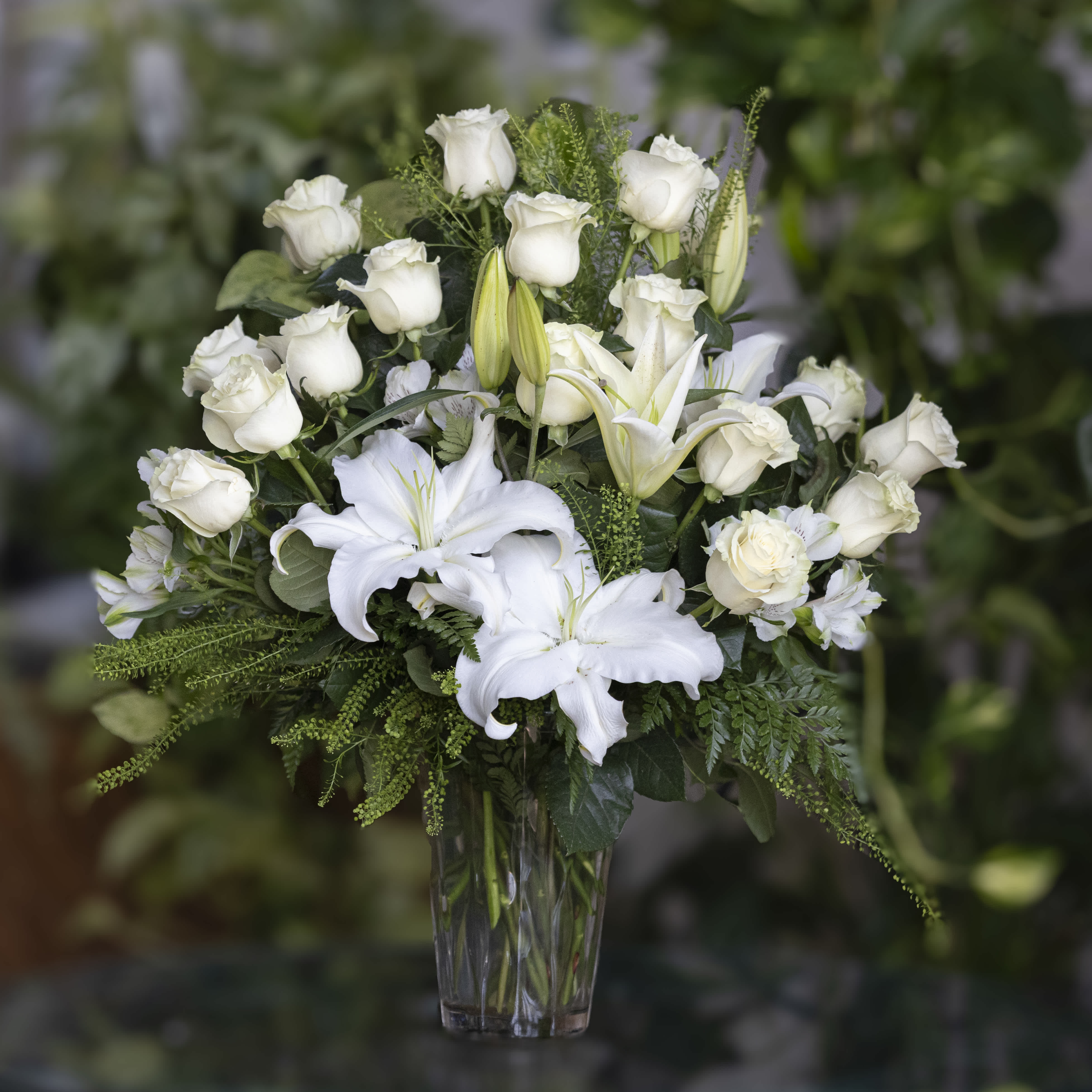 White roses and lilies arranged in a clear glass vase