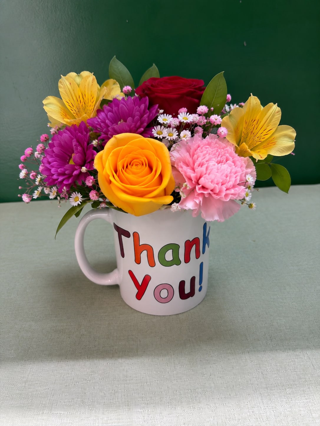 Mixed flower bouquet in a white mug that says Thank You