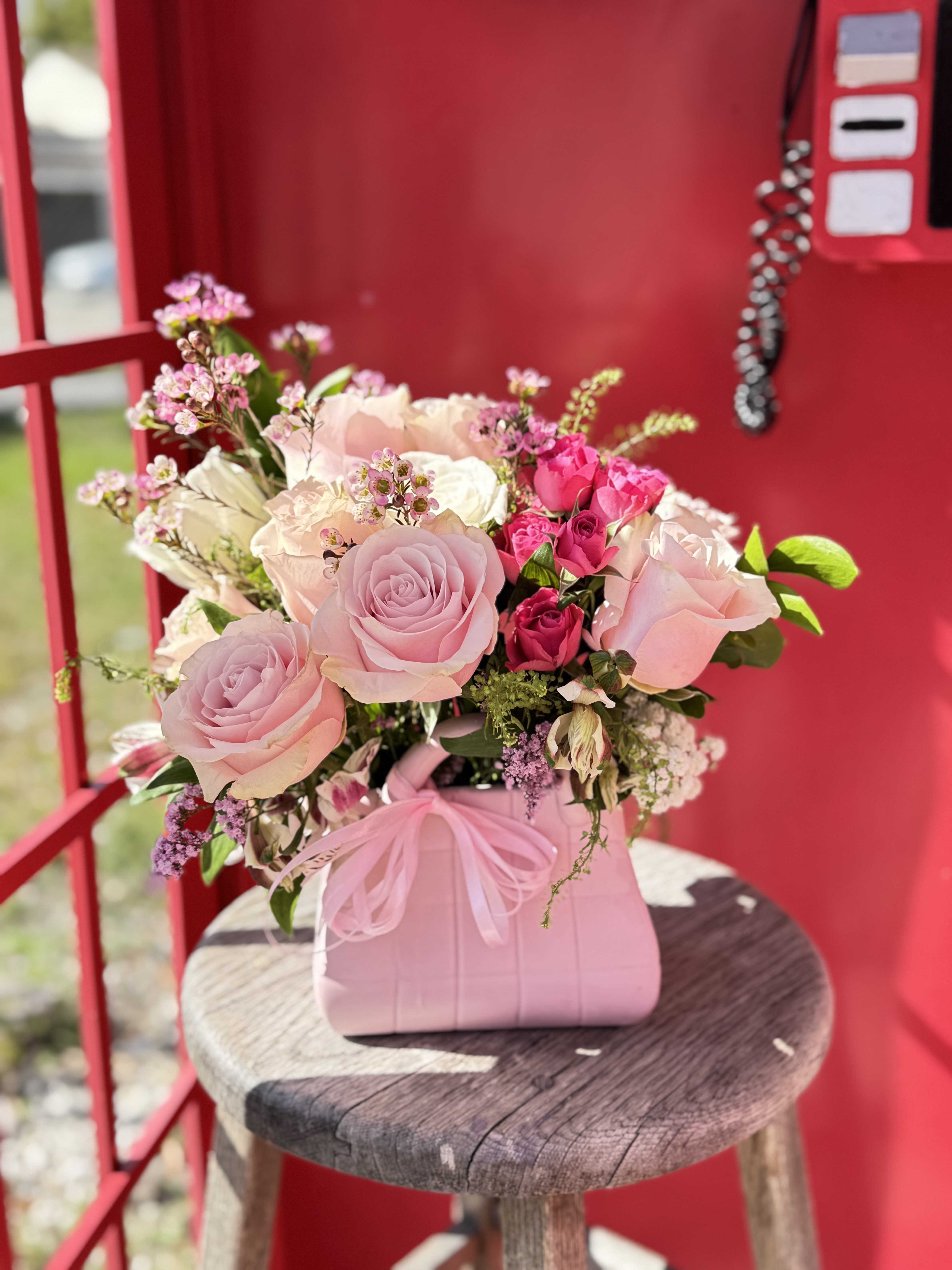 Pink and white rose bouquet in a pink handbag-style container