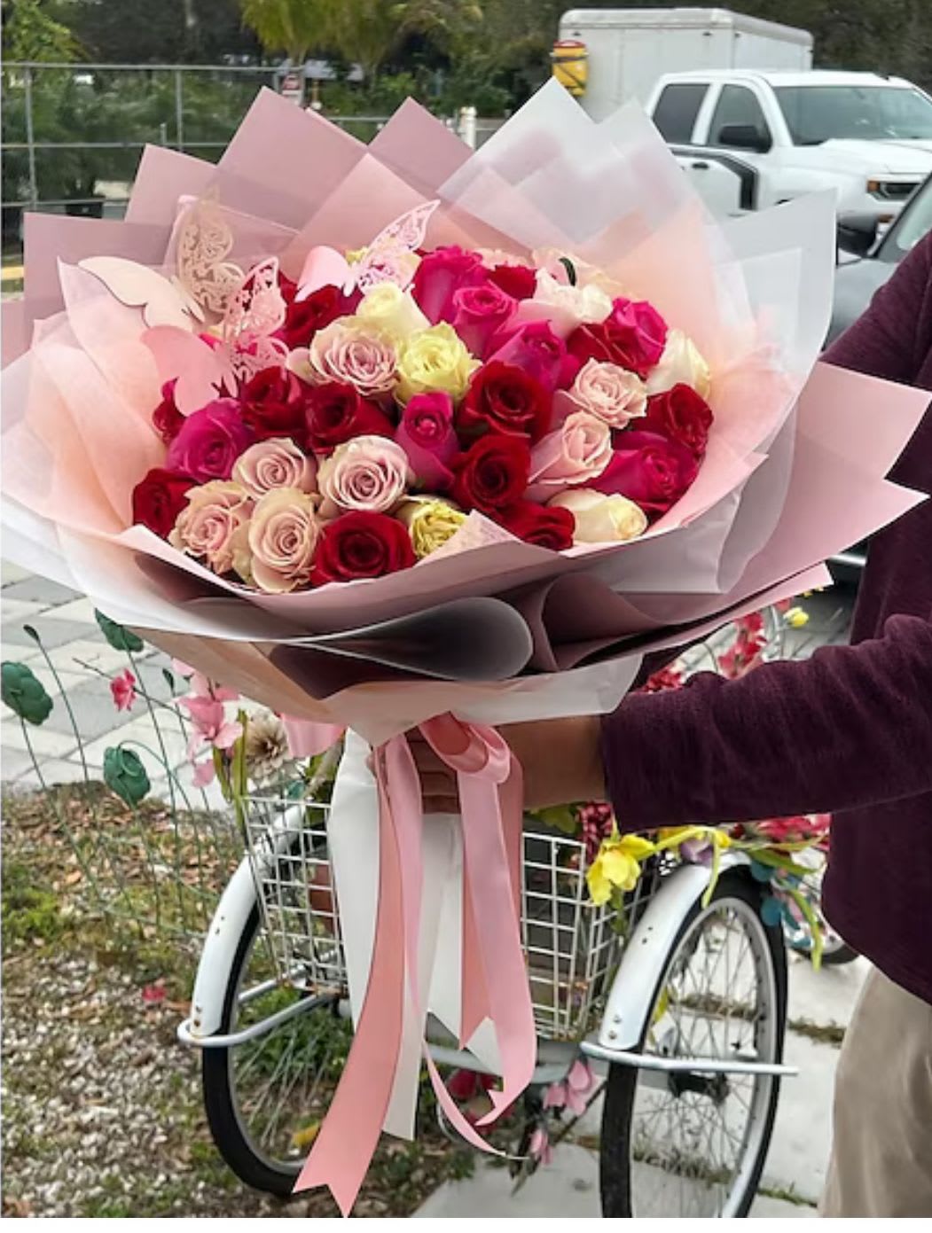 Large bouquet of pink, red, and cream roses wrapped in pastel paper