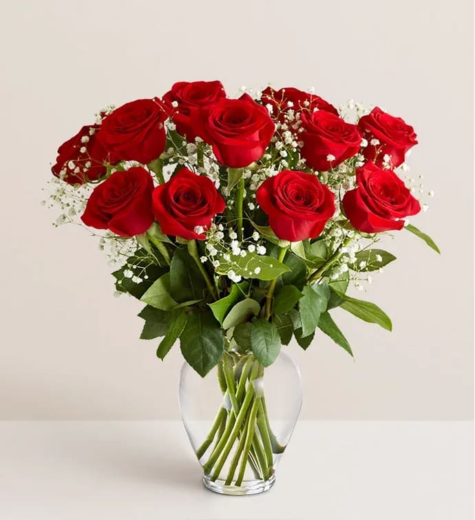 Red roses arranged in a clear glass vase with white baby's breath