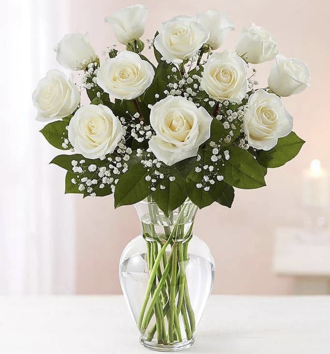 White roses arranged in a clear glass vase with baby's breath