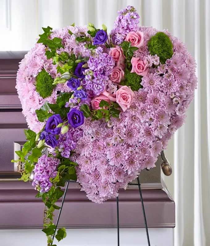 Heart-shaped floral arrangement of pink and purple flowers on an easel