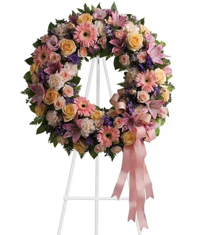 Pastel floral wreath with pink ribbon on a white stand