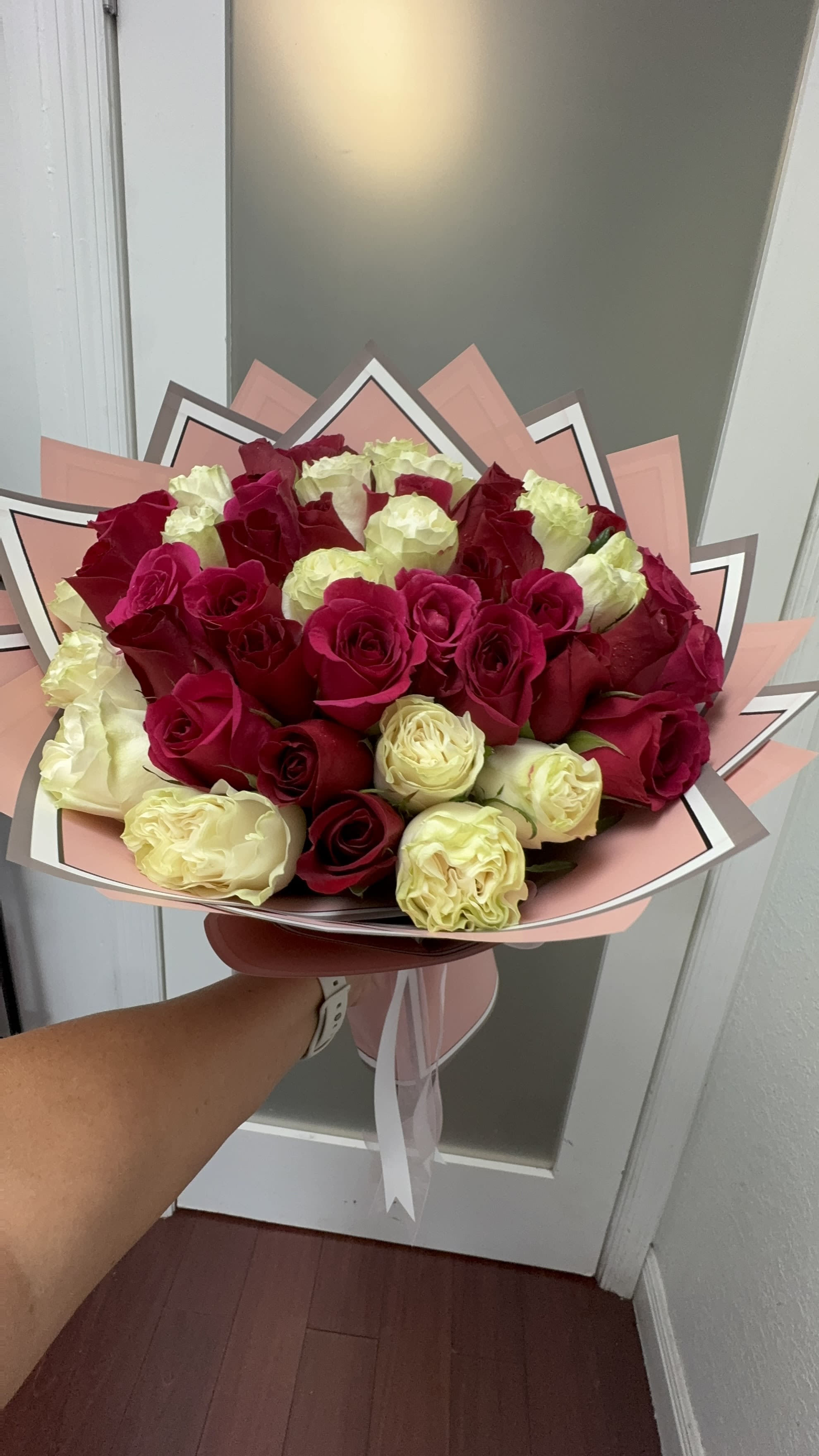 Bouquet of red and cream roses wrapped in pink paper