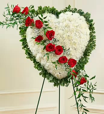 Heart-shaped white floral spray with red roses on a stand