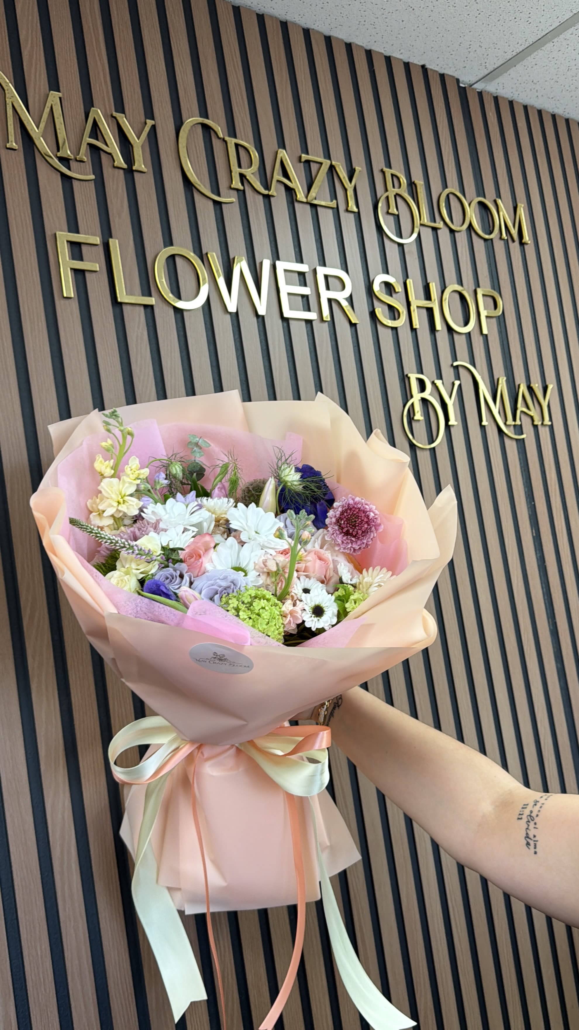 Pastel mixed flower bouquet wrapped in pink paper with ribbon