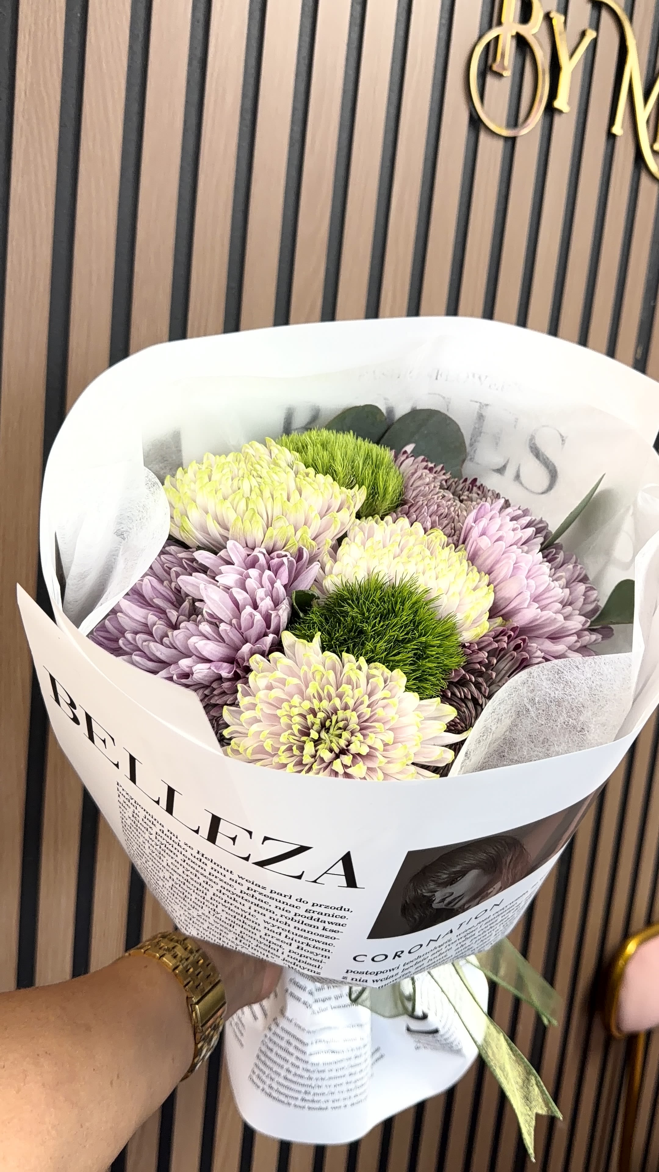 13 de Diciembre  - Soft lavender and creamy yellow-white chrysanthemums form a gently rounded bouquet that reads fresh, modern, and quietly joyful-perfect as a birthday bouquet, a spring gift, or a simple thank-you arrangement. The mix of pastel blooms with bright green pom‑pom accents creates a soft, textured look that will make the person you're thinking of feel noticed and cheered without being over the top.  Hand-tied and wrapped in white printed paper with a coordinating ribbon, this arrangement has an editorial, polished presentation that still feels casual enough for everyday giving. The compact, rounded cluster is easy to display on a table or bedside and highlights the full, ruffled petals of the chrysanthemums alongside the button-like green accents for contrast and depth. Order for same-week delivery to brighten someone's day with a clean, cheerful bouquet that reads both thoughtful and effortless.