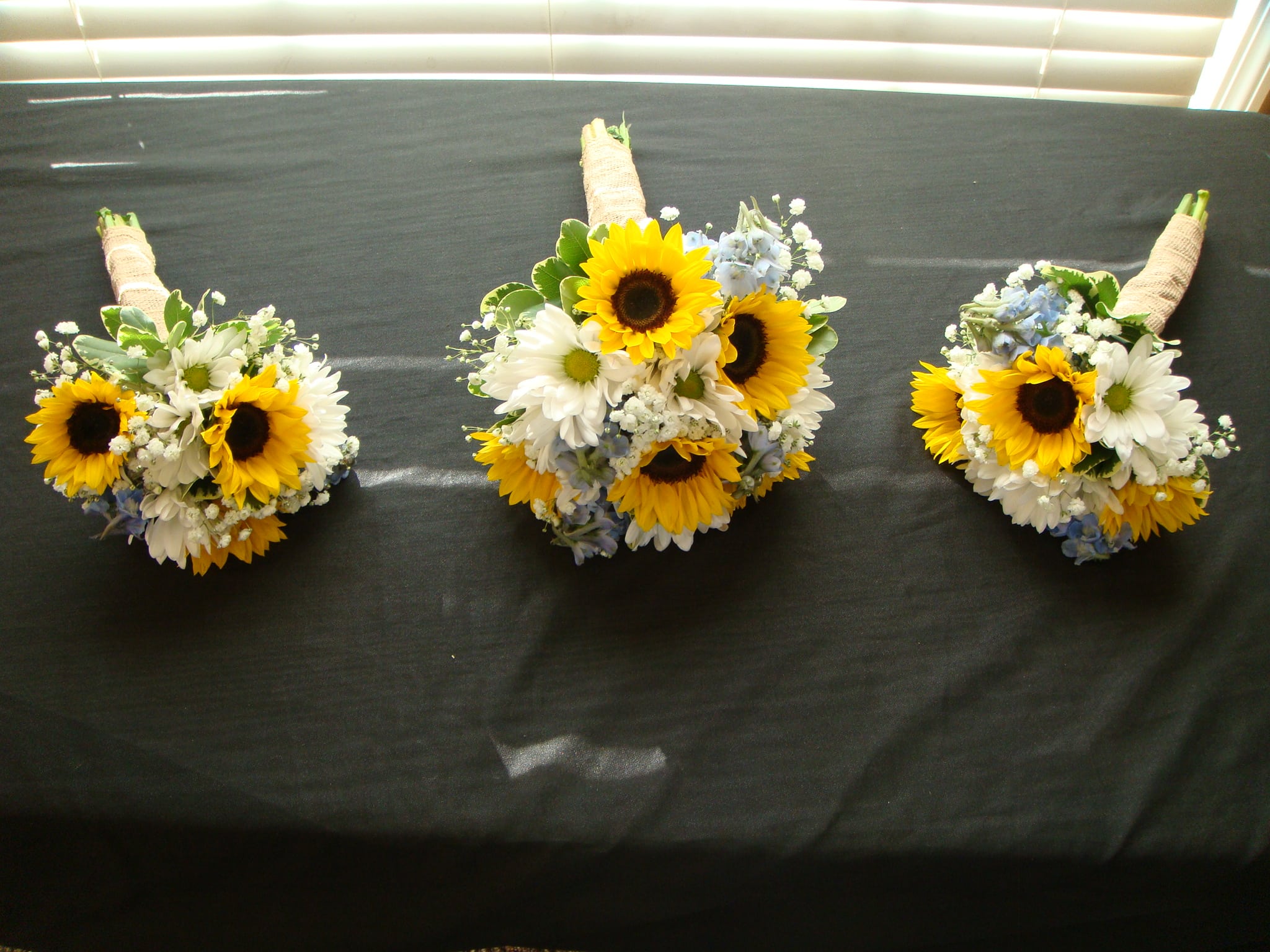 Three sunflower and daisy bouquets with wrapped handles