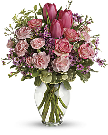 Pink tulips and roses arranged in a clear glass vase