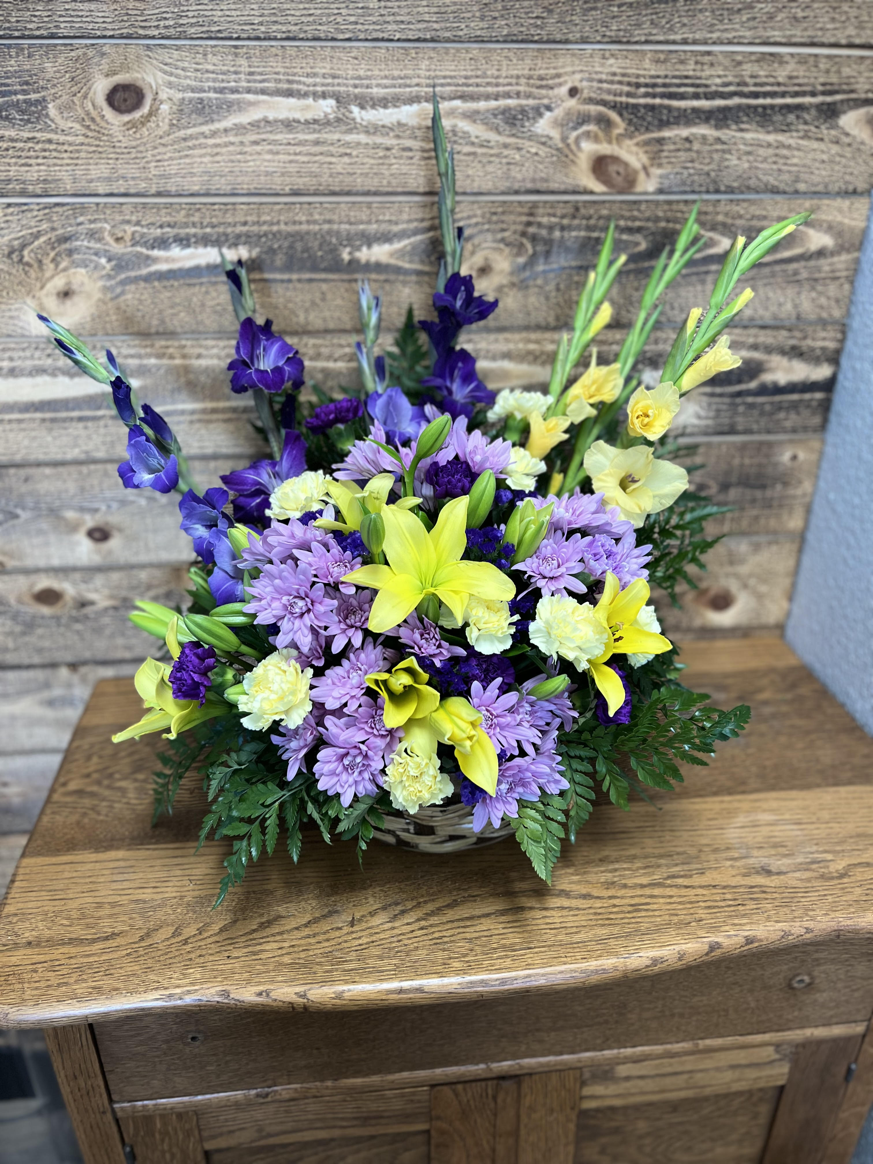 Basket arrangement of purple daisies and yellow lilies