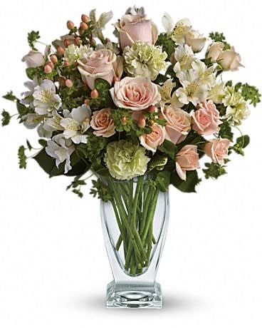 Pink roses and white flowers arranged in a clear glass vase