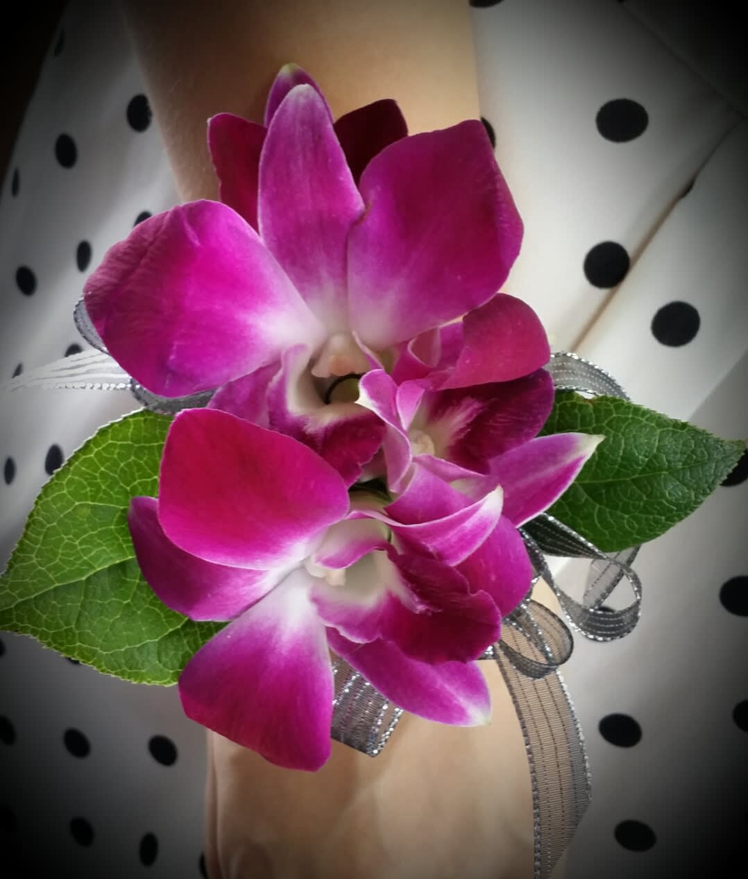 Pink orchid corsage with ribbon and green leaves