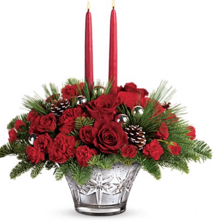 Red roses and pine in a clear glass vase with two red taper candles