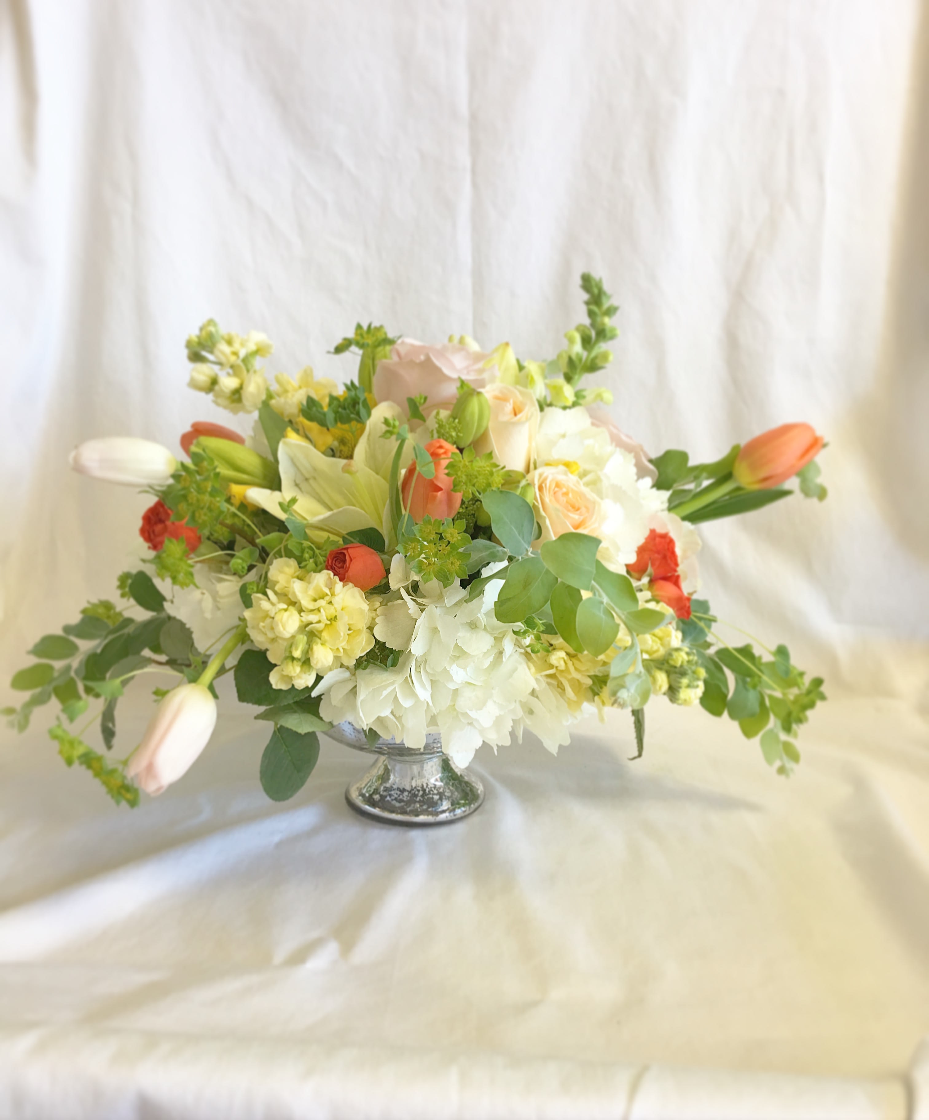 Mixed bouquet in a silver pedestal vase with white and peach flowers