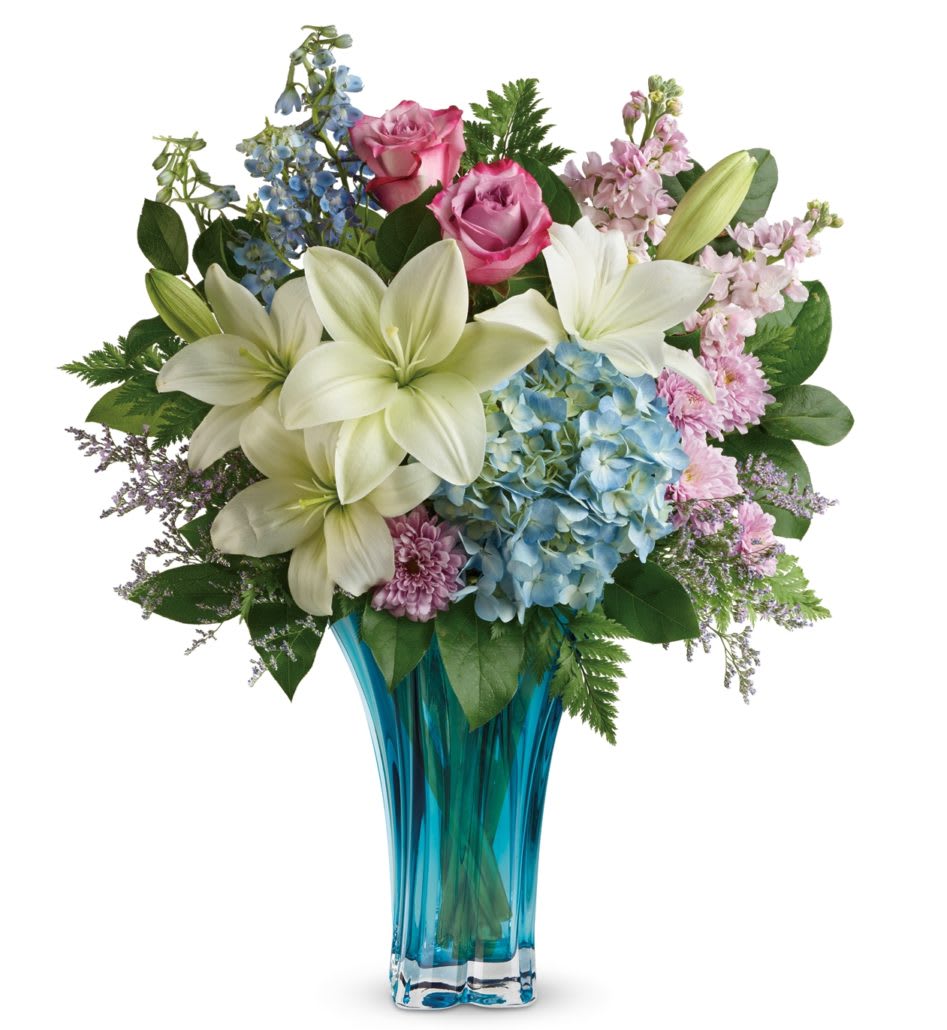 Bouquet of lilies, roses, hydrangea, and mixed blooms in a blue glass vase