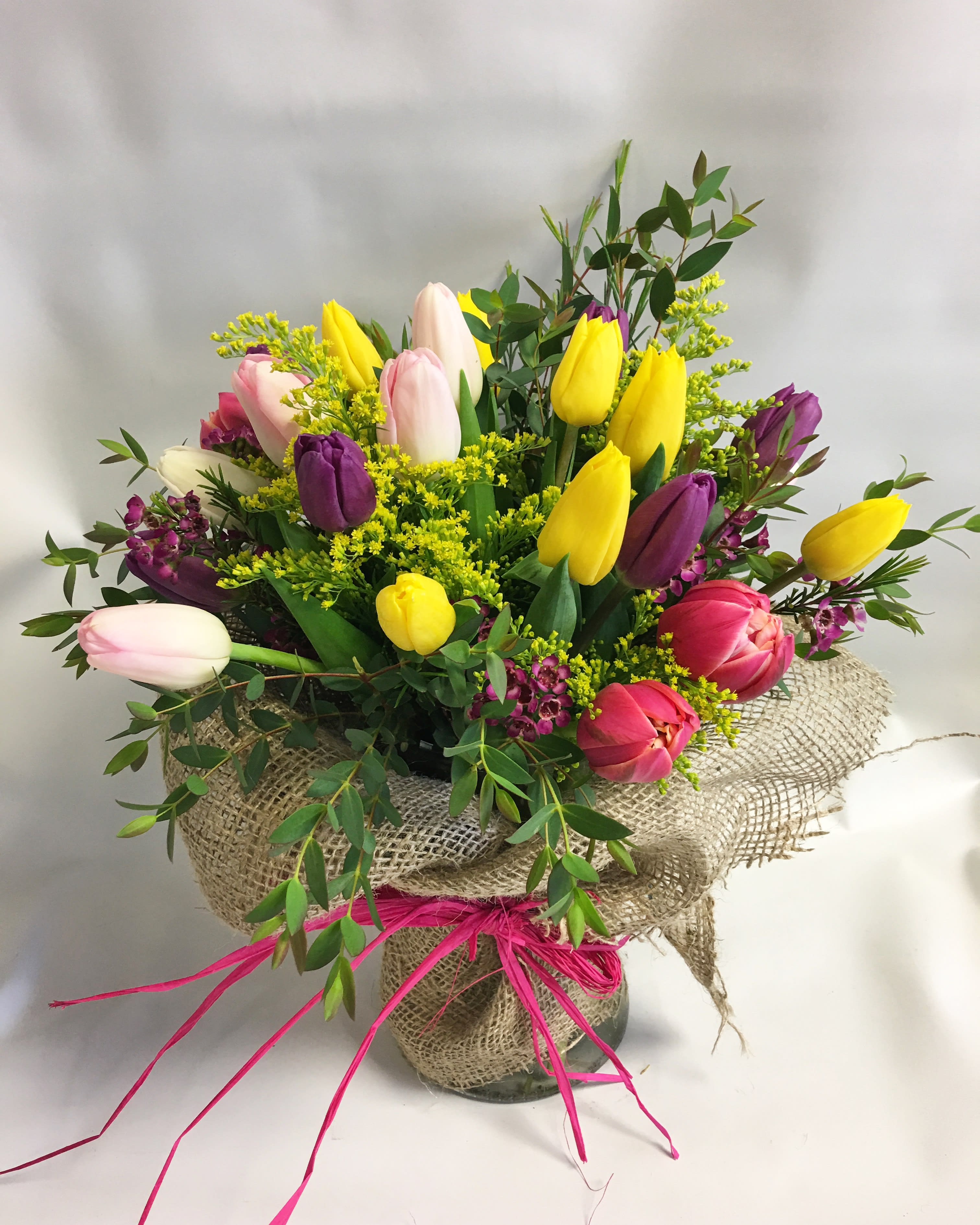Bouquet of multicolored tulips in a burlap-wrapped vase