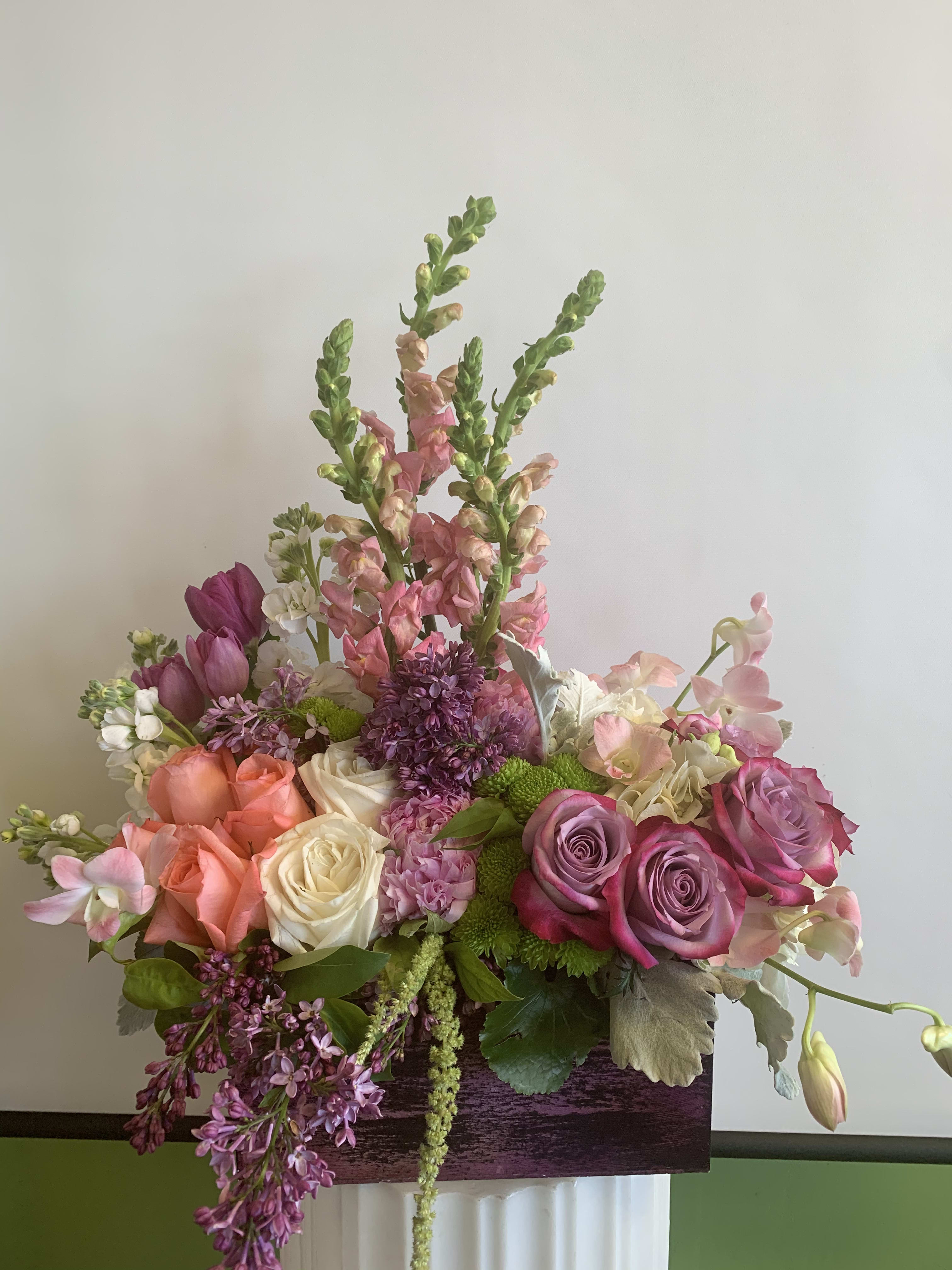 Mixed bouquet of pink, peach, and white flowers in a rectangular container