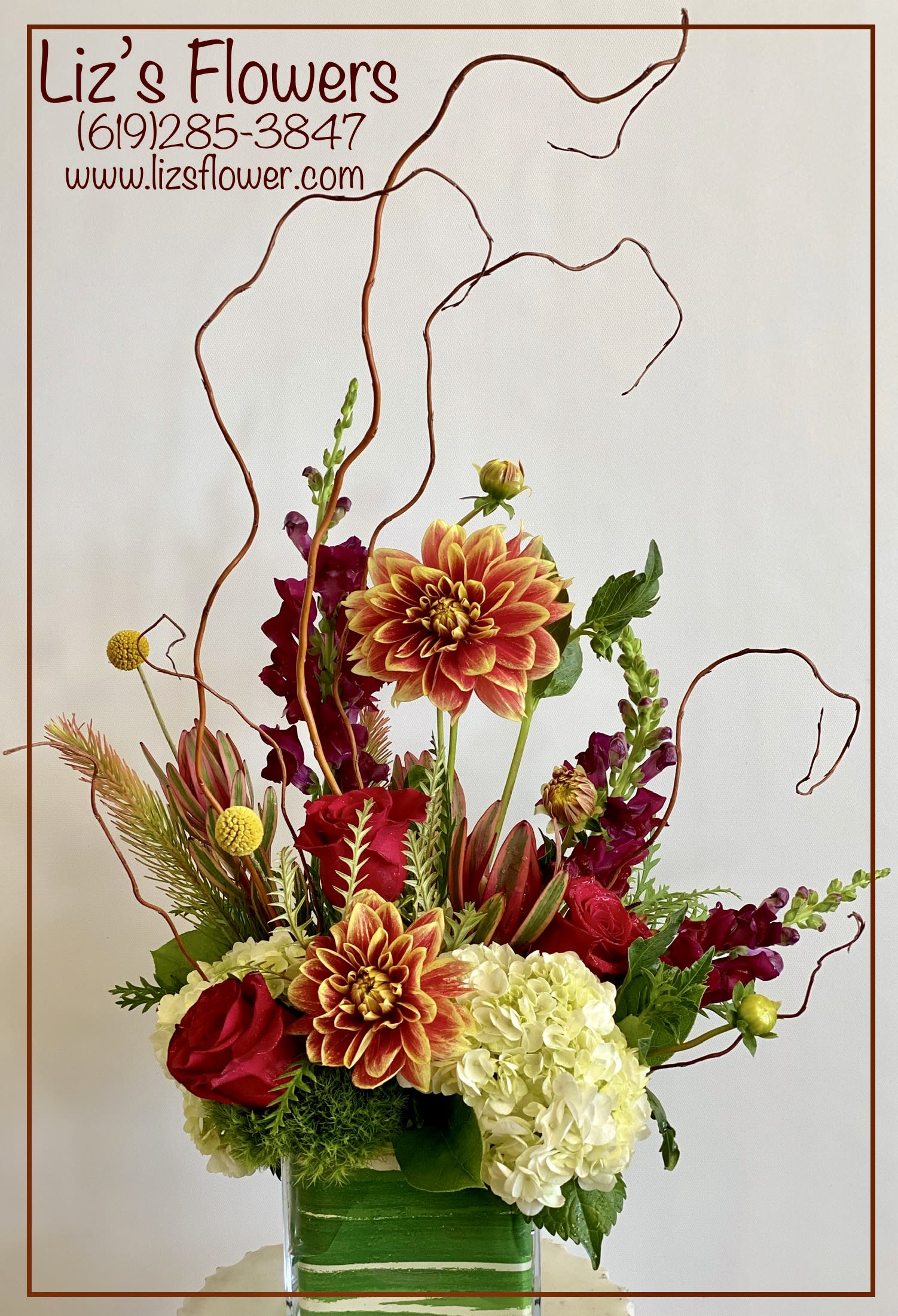 Mixed floral arrangement in a glass vase with red, orange, and white blooms