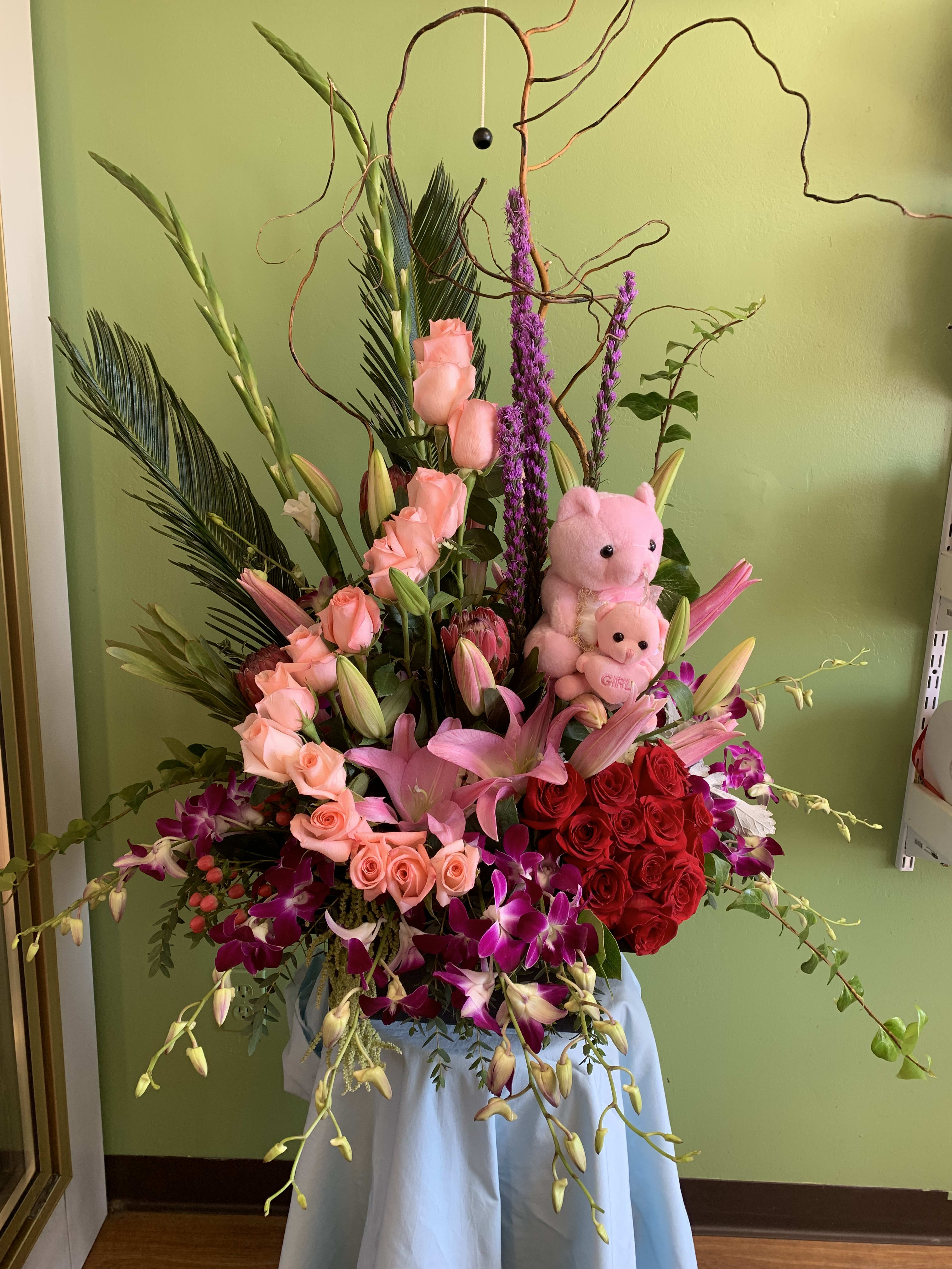 Large pink and red floral arrangement with two teddy bears