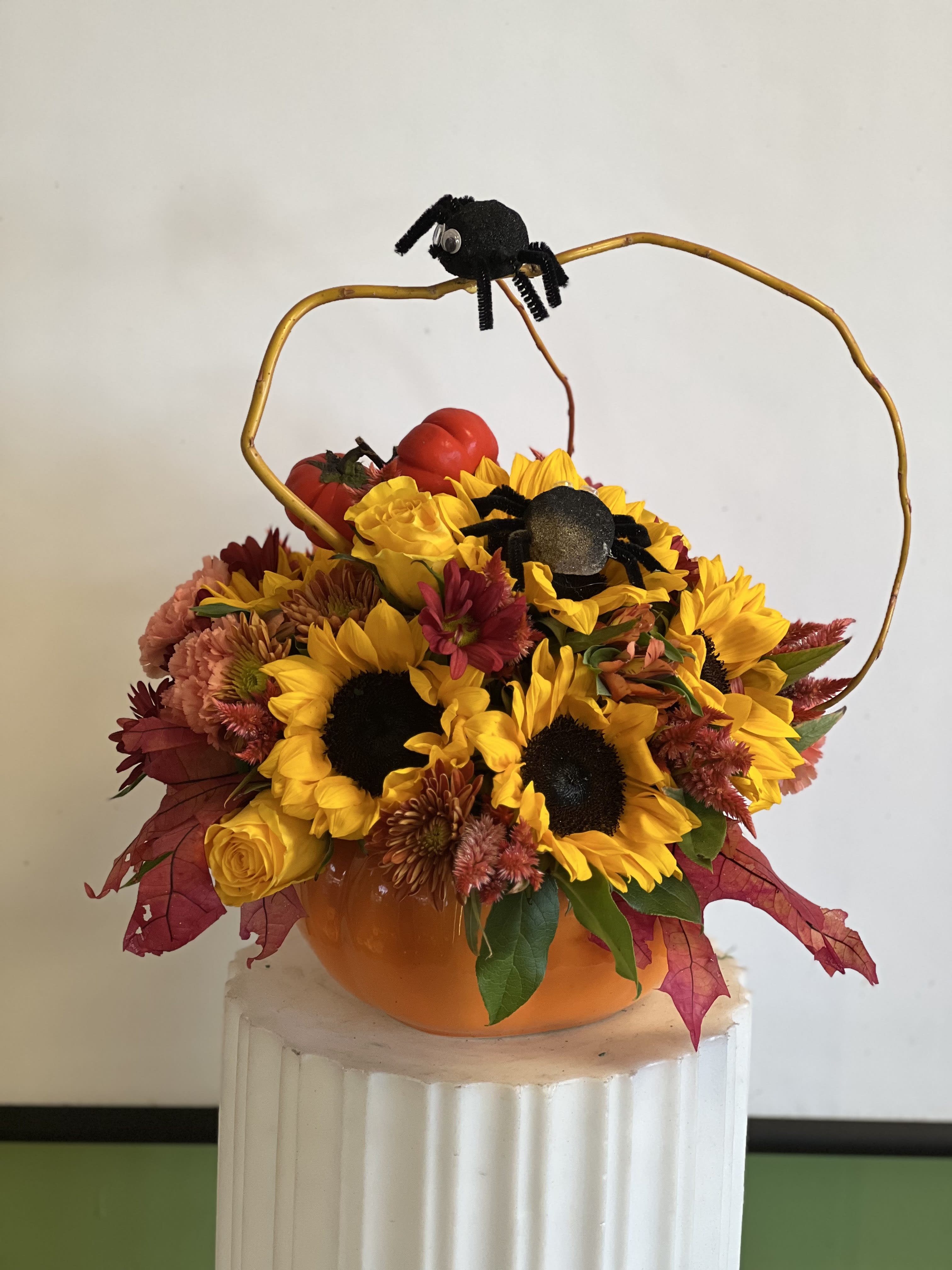 Pumpkin-shaped floral arrangement with sunflowers and black spider decorations