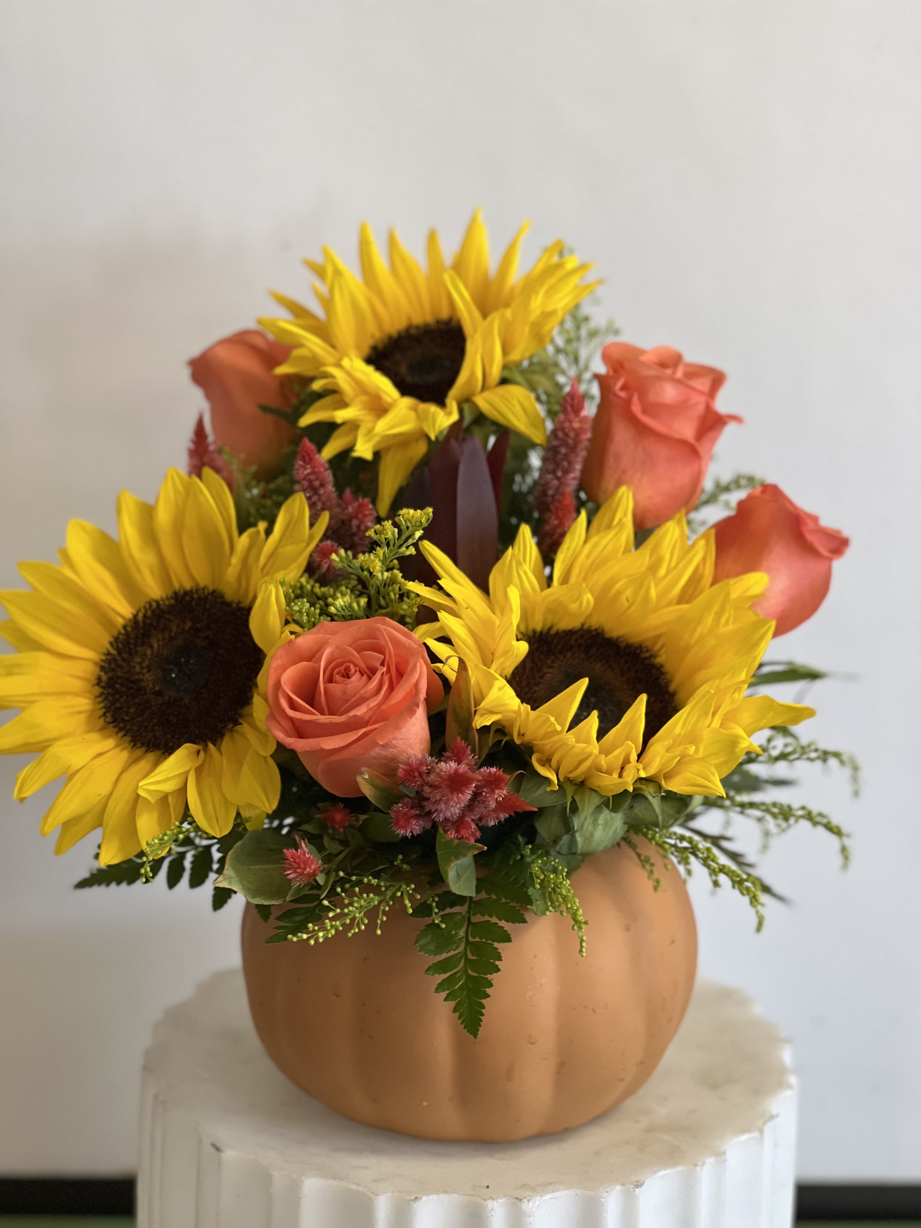 Sunflowers and coral roses arranged in a pumpkin-shaped vase