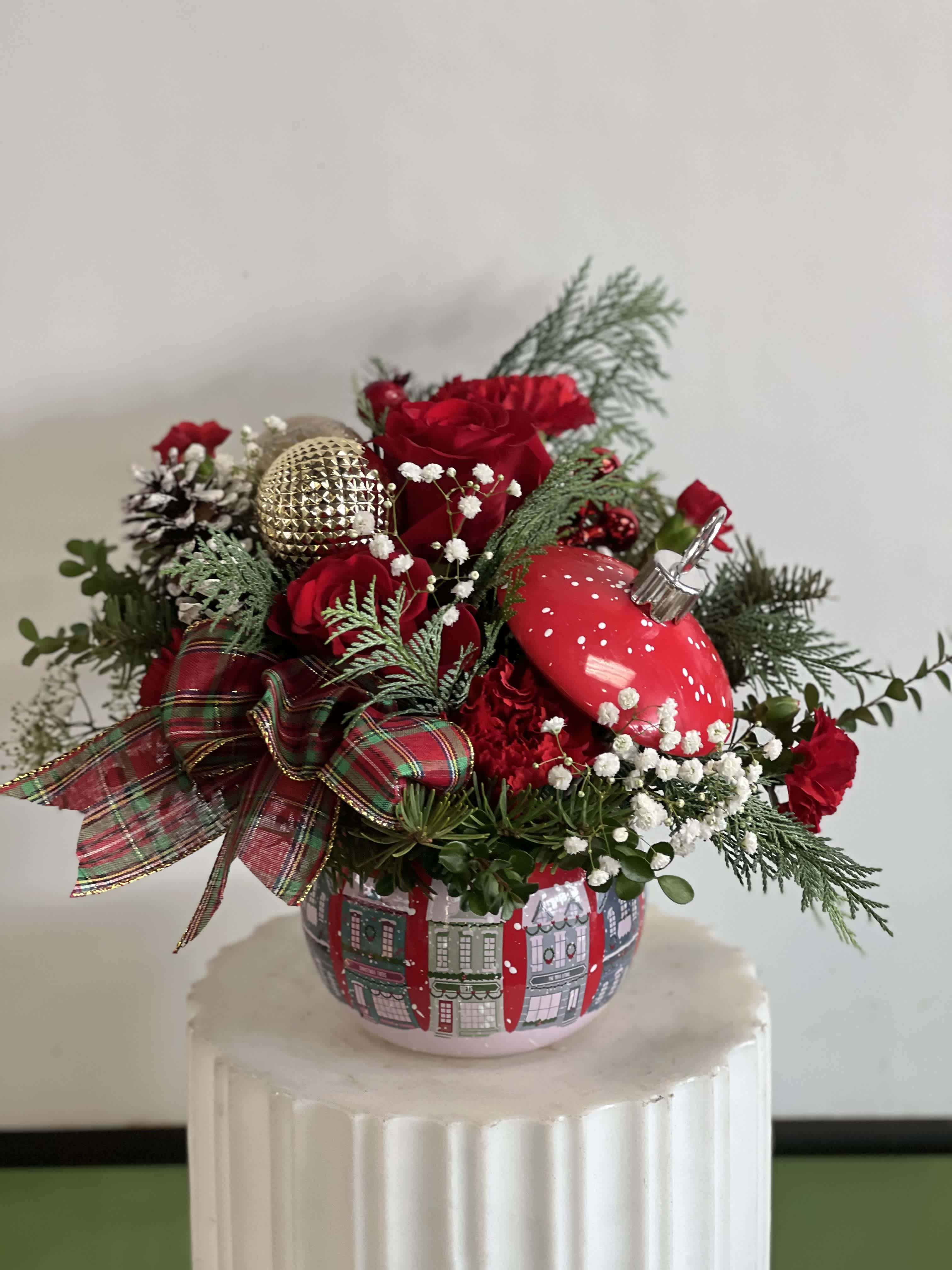 Red roses in a festive holiday arrangement with ornaments in a decorative pot