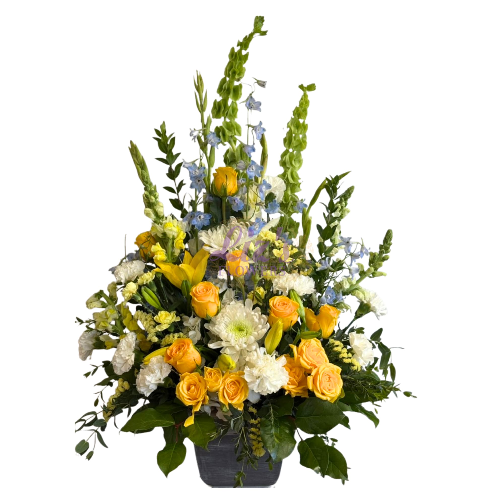Tall mixed bouquet of yellow roses, white blooms, and blue flowers in a dark vase