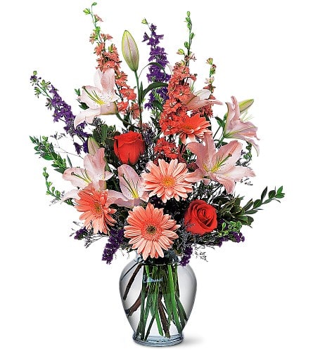 Mixed bouquet of lilies, roses, and daisies in a glass vase