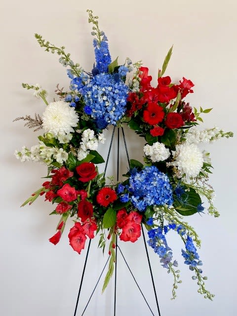 Red, white, and blue floral wreath on a black easel