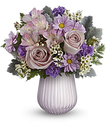 Lavender and white flower arrangement with roses and daisies in a ribbed lavender glass vase